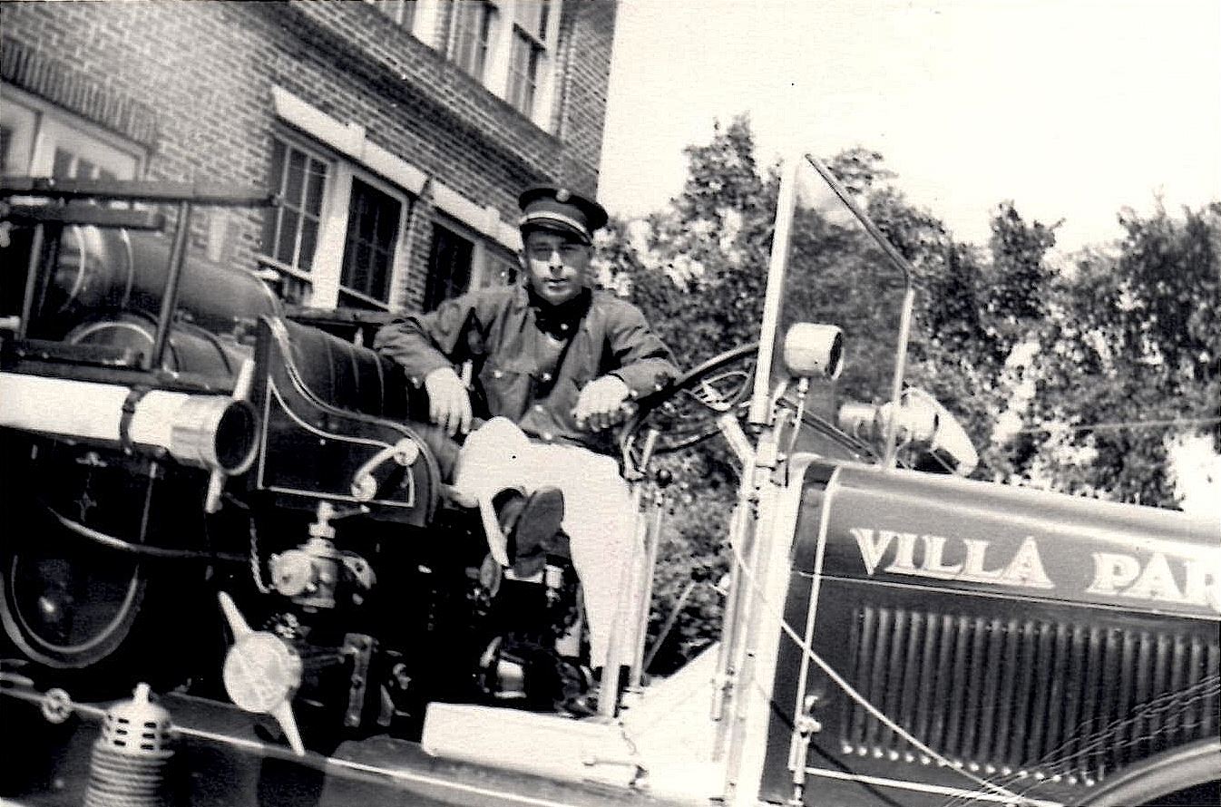 Villa Park Firefighter Bill Rutter sits in the driver's seat of a 1938 Pierce fire truck outside of Village Hall.